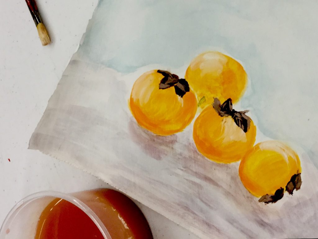 4 x orange fruit painted onto paper, paint brush and water cup for brush rinsing