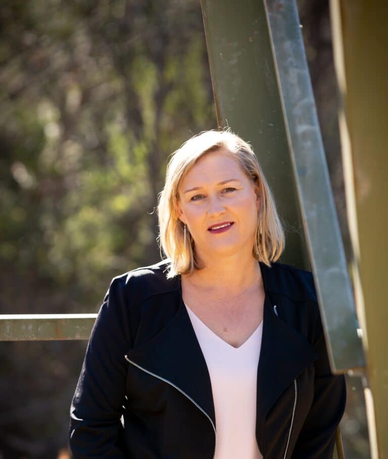 Professional woman in black blazer smiling outdoors