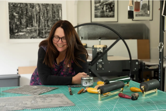 Artist smiling at printing press in studio workspace