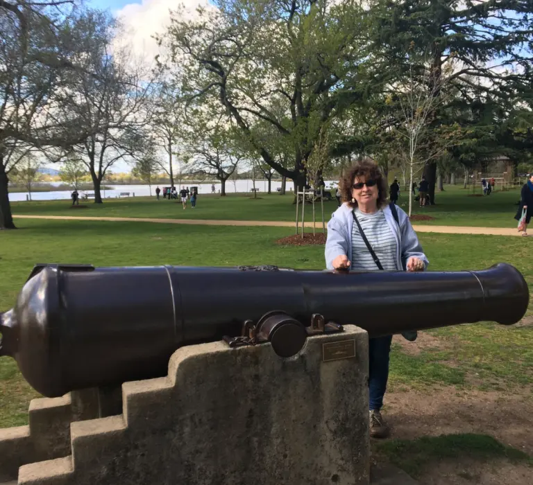 Woman posing behind historic cannon in lakeside park