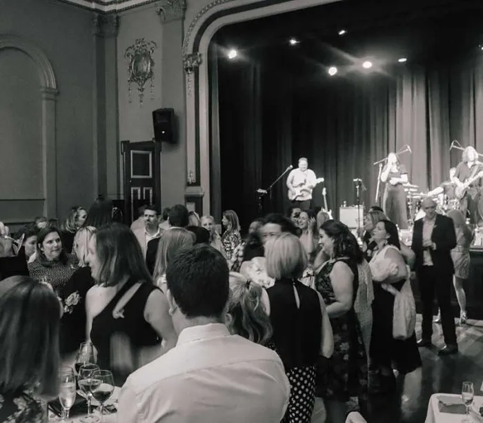 Crowd dancing at formal gala event with live band on stage