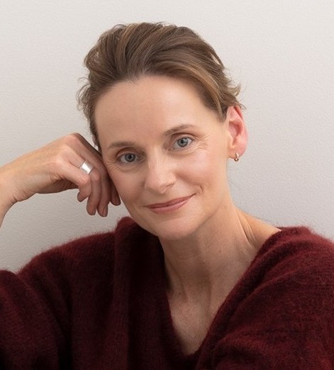 Woman in burgundy jumper smiling warmly at camera