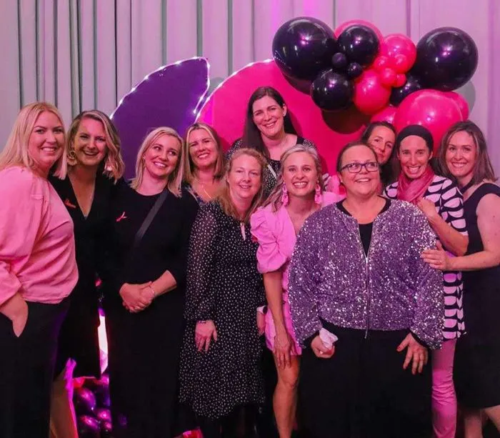 Group of women posing at pink and black balloon event