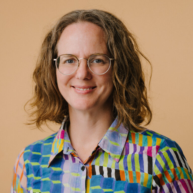 Smiling woman with glasses and colourful patterned shirt