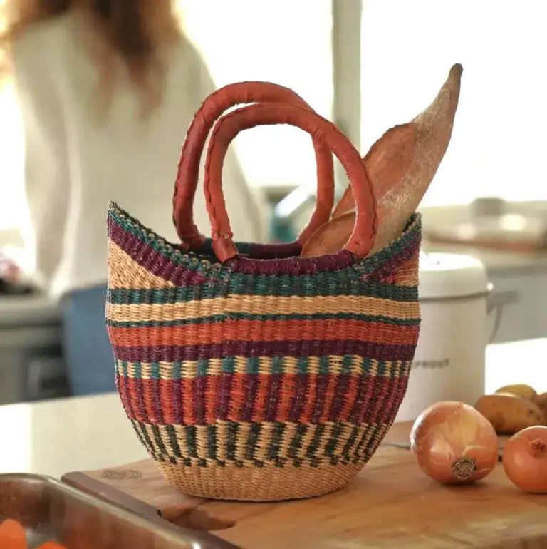 Colourful woven African basket with leather handles on kitchen bench
