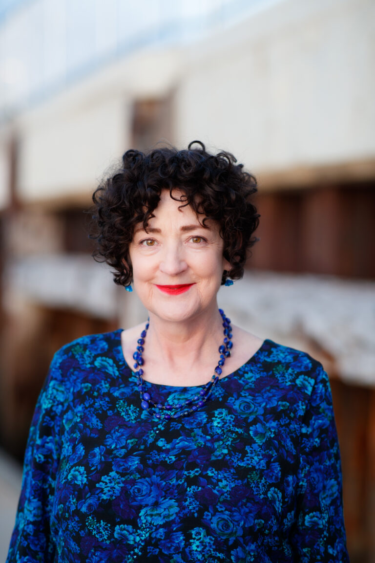 Woman with curly hair smiling in blue floral top