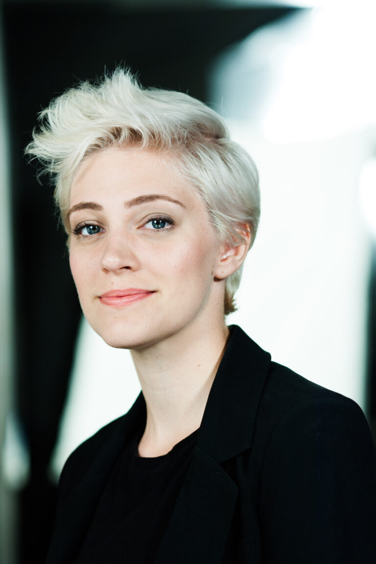 Young woman with platinum blonde pixie cut smiling confidently