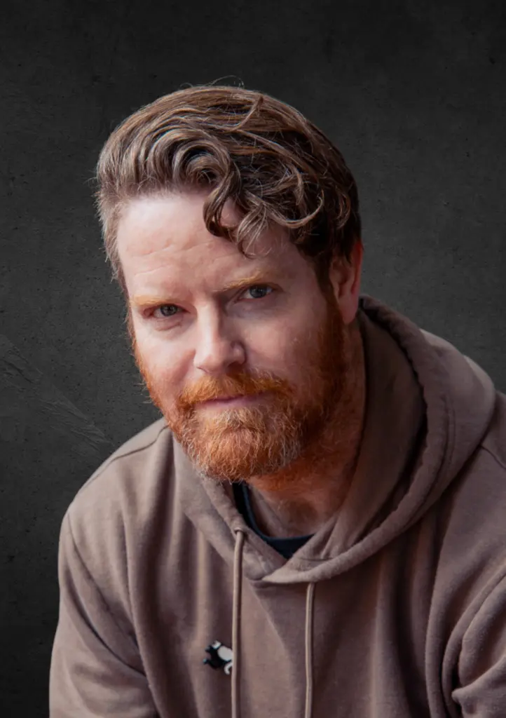 Man with red beard and wavy hair in studio portrait