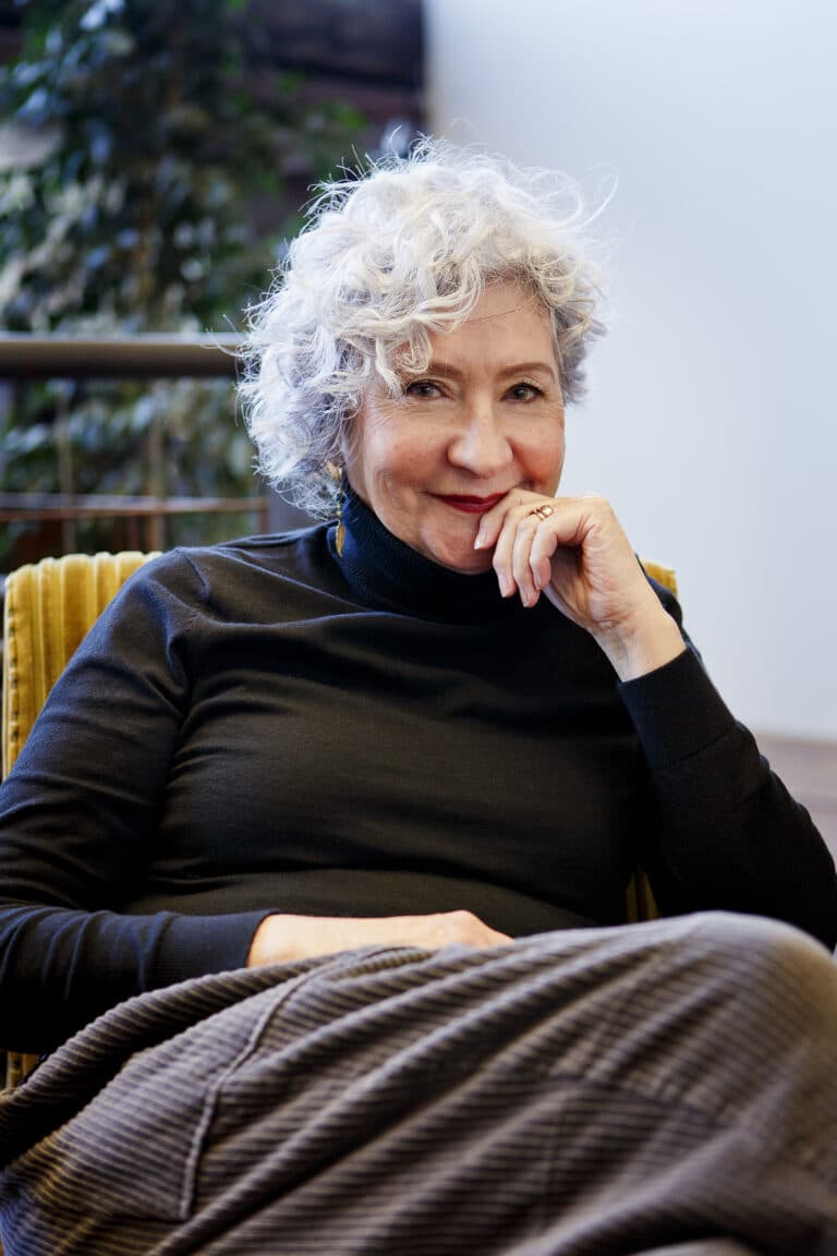 Elegant older woman with white curly hair smiling confidently