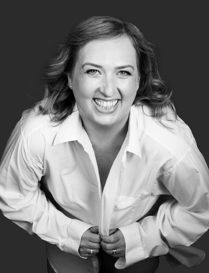 Woman in white shirt smiling confidently in studio portrait