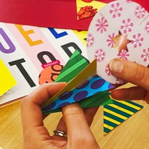 Hands crafting colourful paper decorations at creative workshop