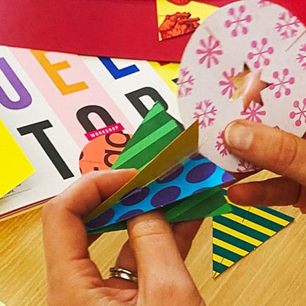 Hands crafting colourful paper decorations at creative workshop