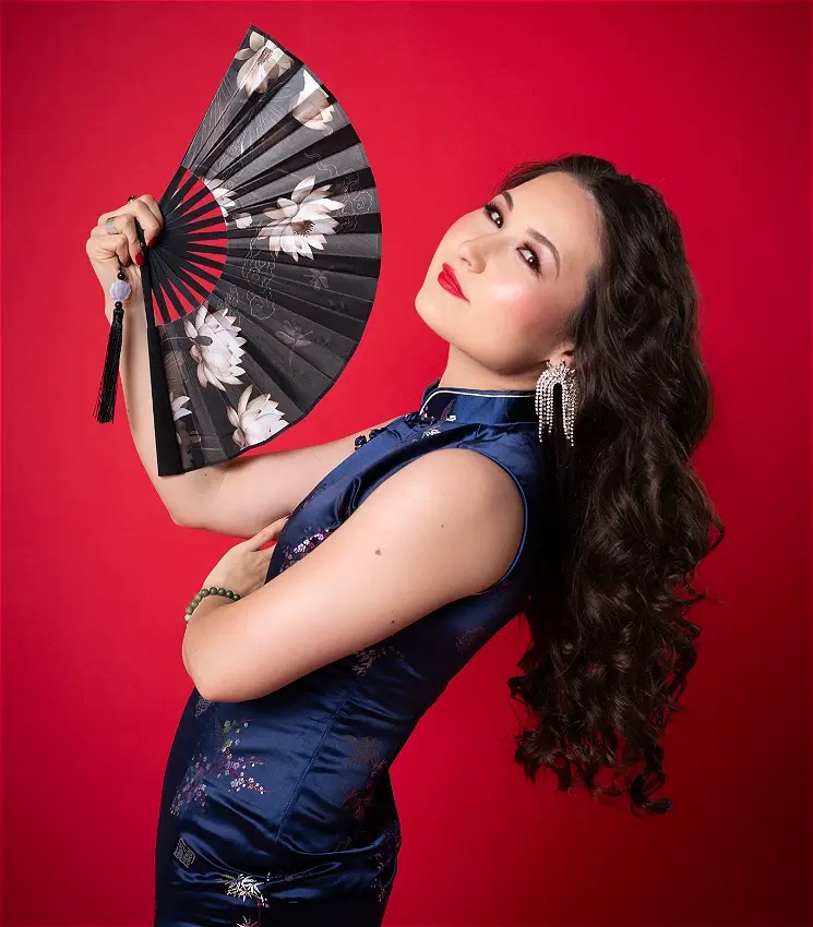 Woman in blue qipao holding decorative black floral fan