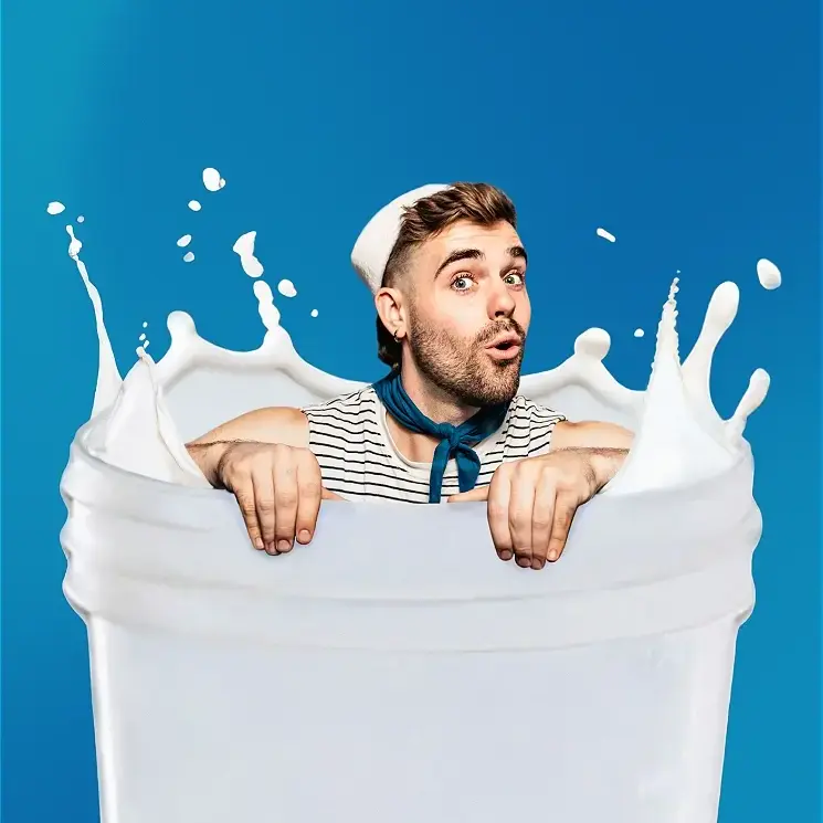 Surprised man emerging from giant splashing glass of milk