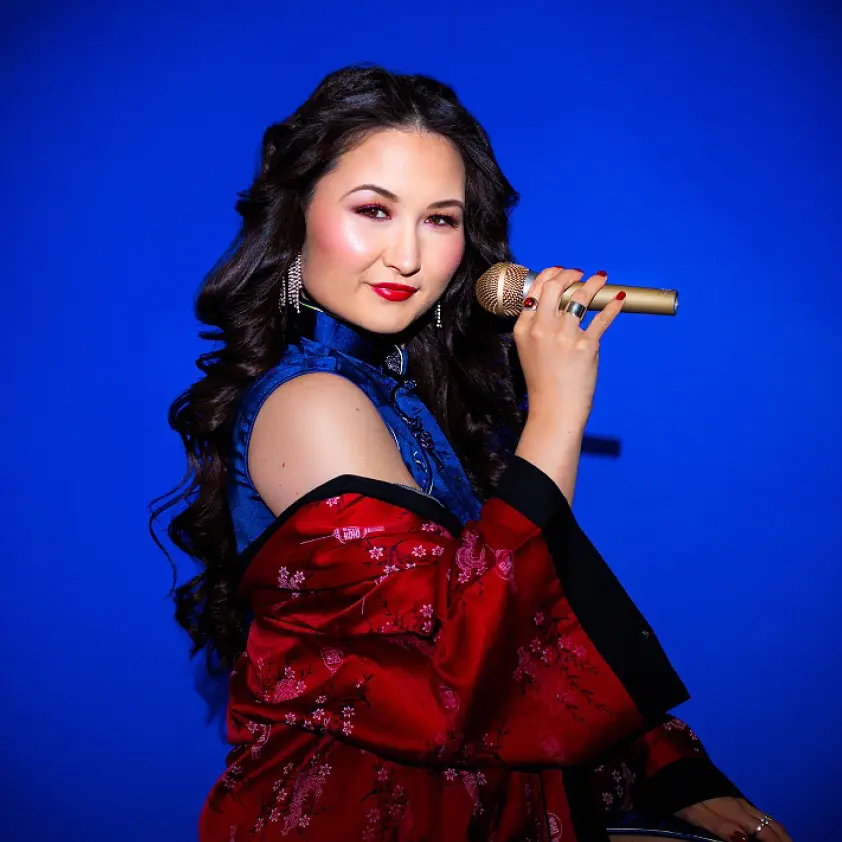 Asian female singer holding gold microphone in traditional attire