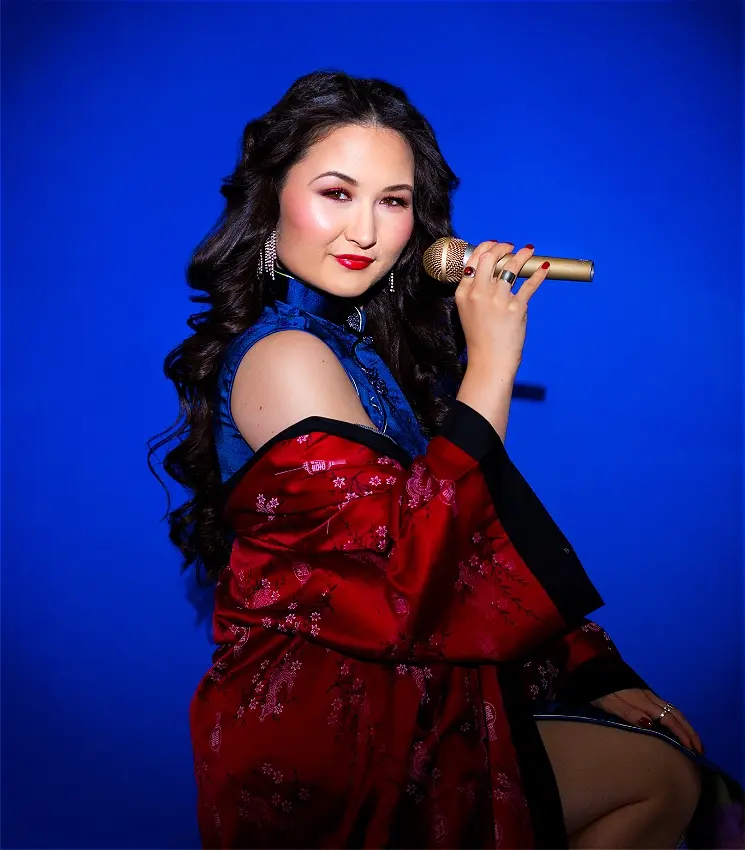 Young woman in traditional Asian attire holding gold microphone